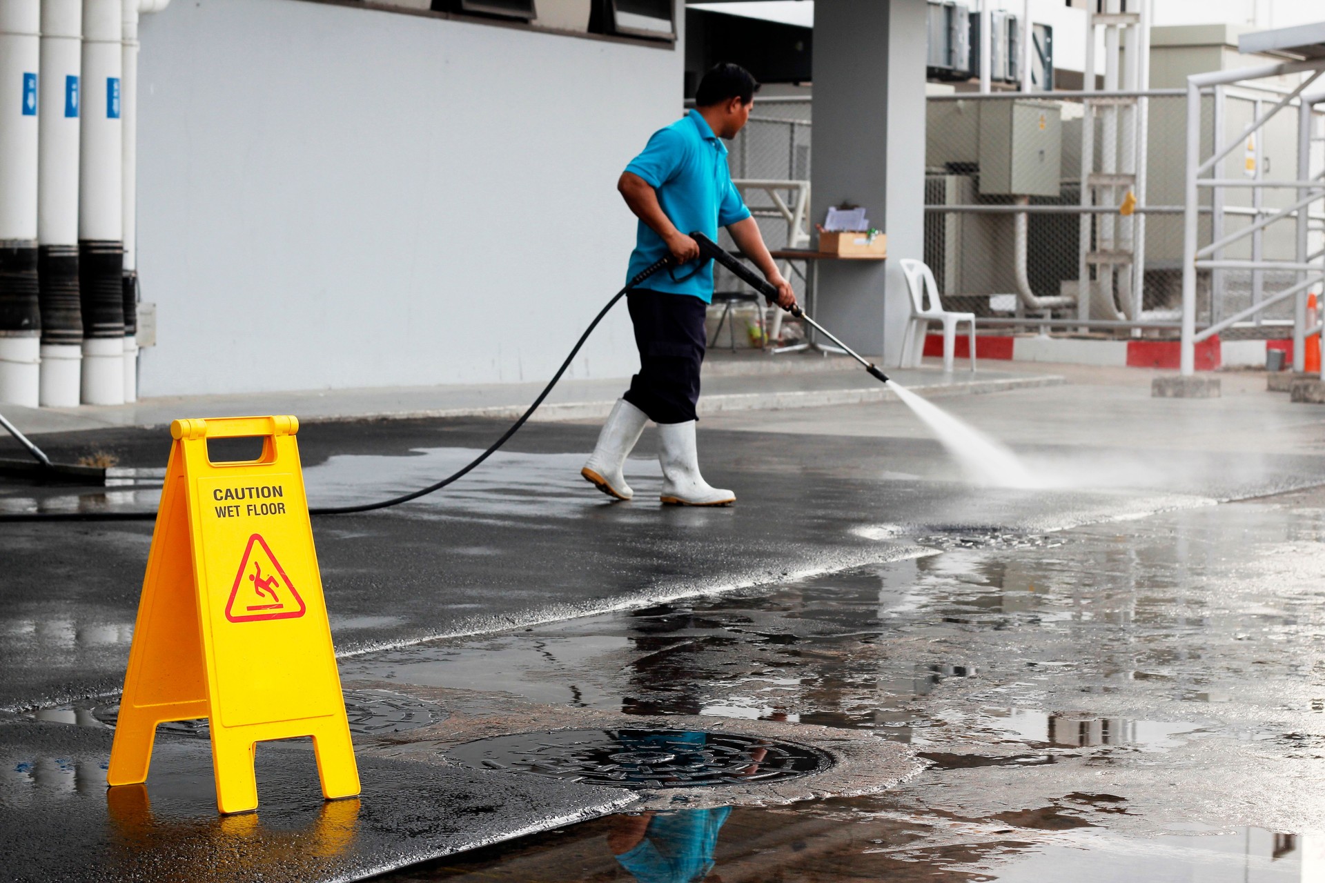 caution wet floor banner and worker cleaning floor